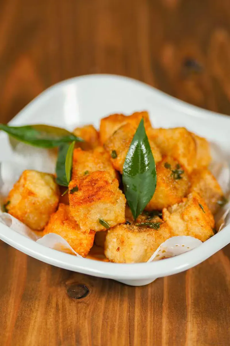 Crispy pan fried tofu cubes garnished with fresh aromatic herb leaves at One More Bite Dumpling, a Chinese Restaurant in Palm Desert