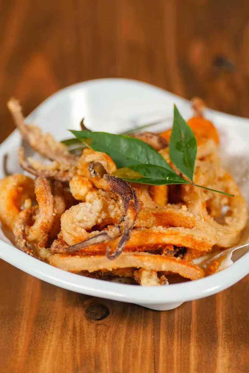 Golden crispy salt and pepper fried squid rings on lined white plate at One More Bite Dumpling, a Chinese Restaurant in Palm Desert